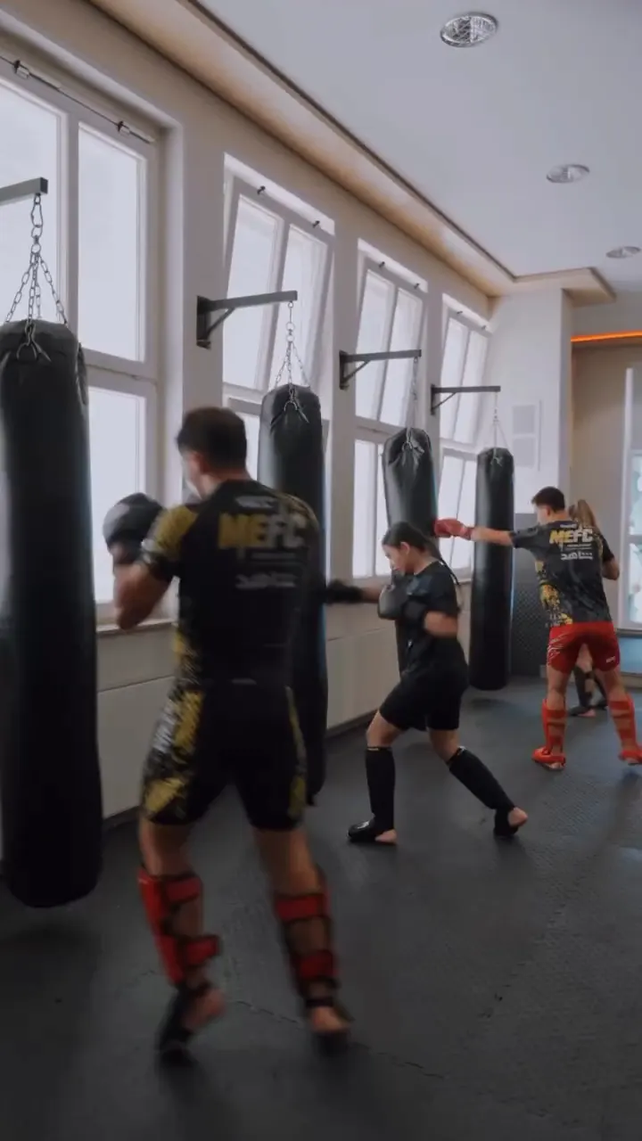 Kickboxer mit Schienbeinschonern an den Sandsäcken